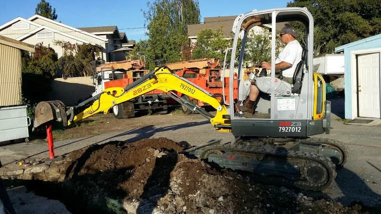 A mini excavator opening the pit at one end of the run.